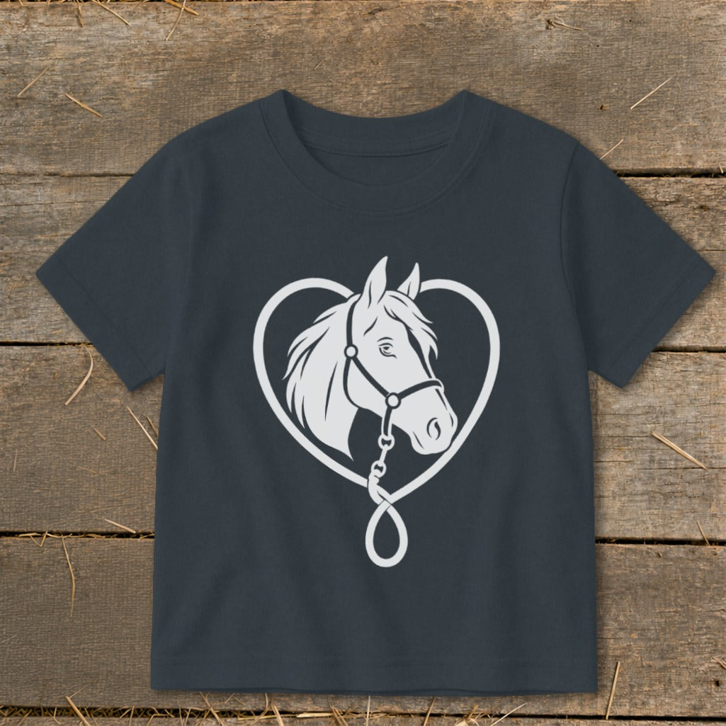 A dark gray t-shirt featuring a white graphic of a horse head inside a heart shape on a wooden background.