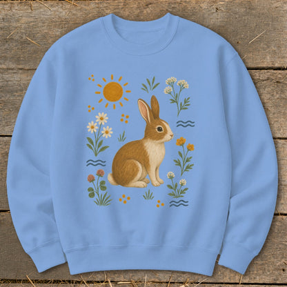 Light blue sweatshirt with a brown and white rabbit surrounded by flowers and the sun.