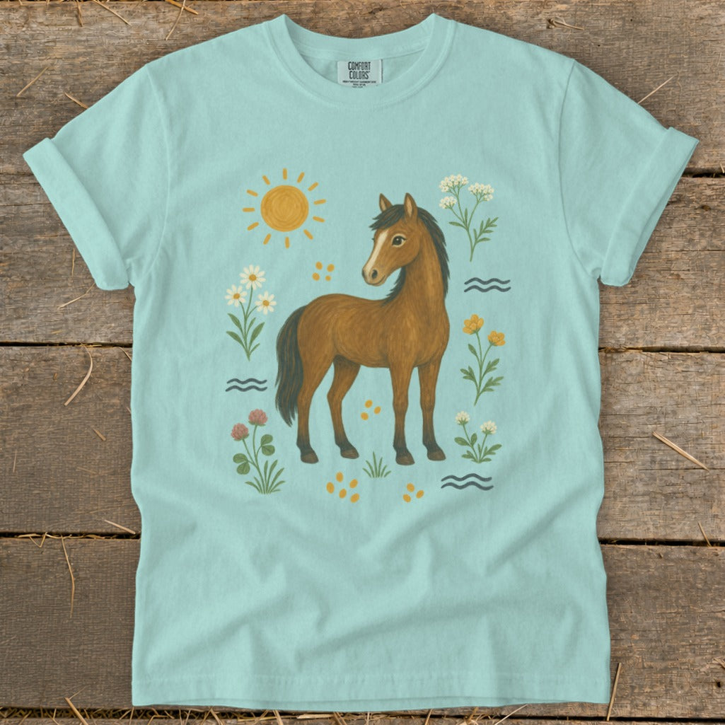 Light blue t-shirt featuring a brown horse surrounded by wildflowers and a sun graphic.
