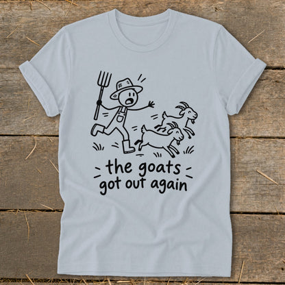 Light blue t-shirt with cartoon farmer chasing escaped goats, text reads "the goats got out again".