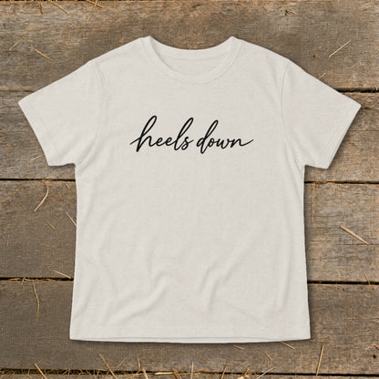 Light beige t-shirt with "heels down" written in black cursive text.