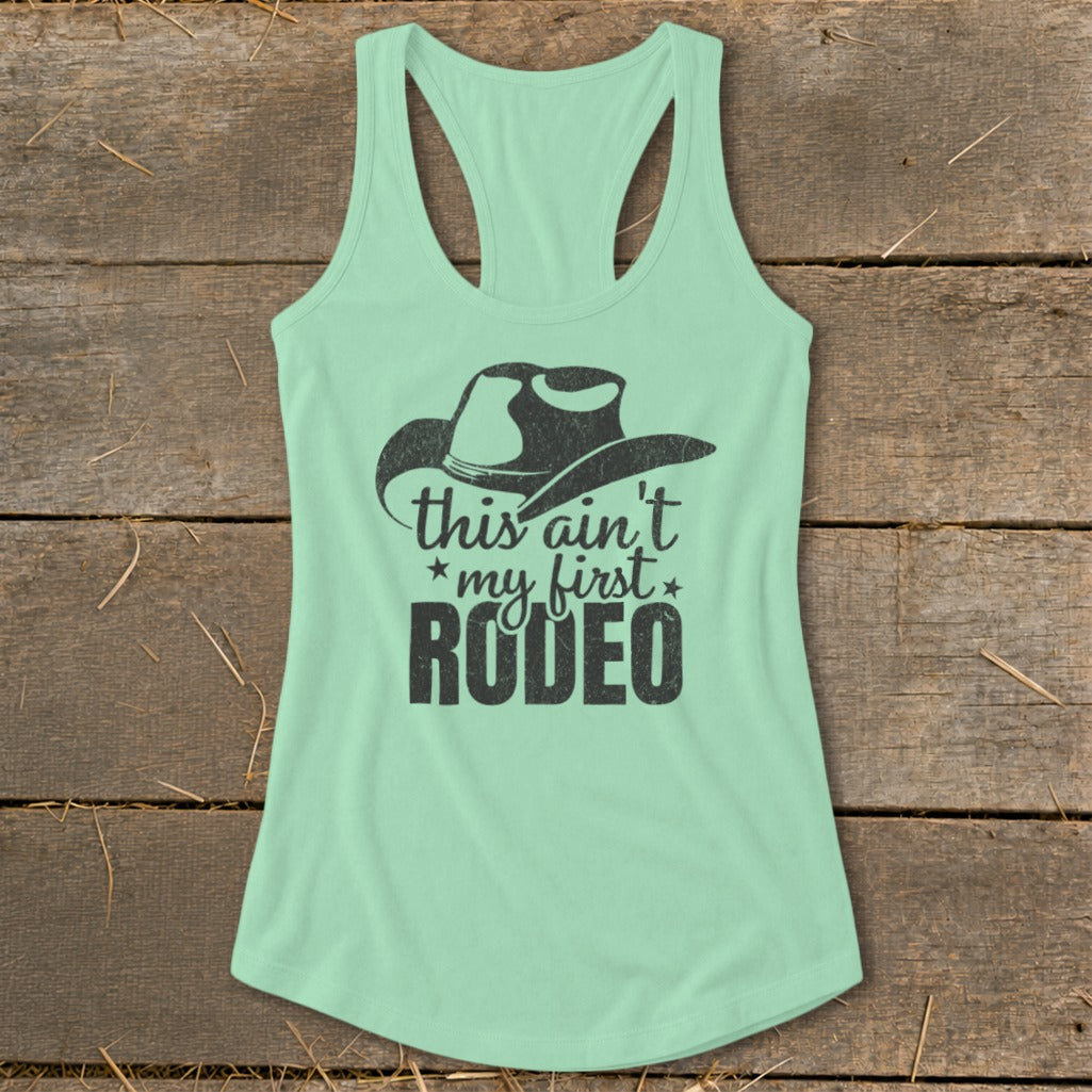 Mint green tank top with black cowboy hat and "this ain't my first RODEO" graphic.