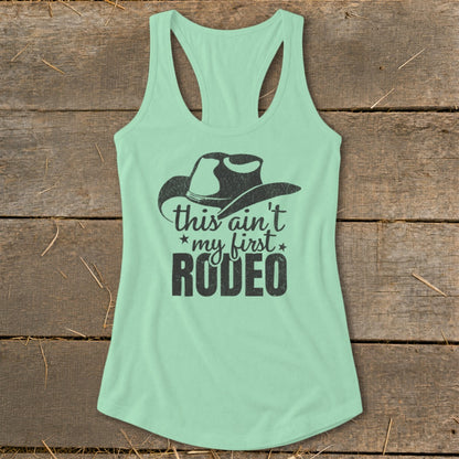 Mint green tank top with black cowboy hat and "this ain't my first RODEO" graphic.