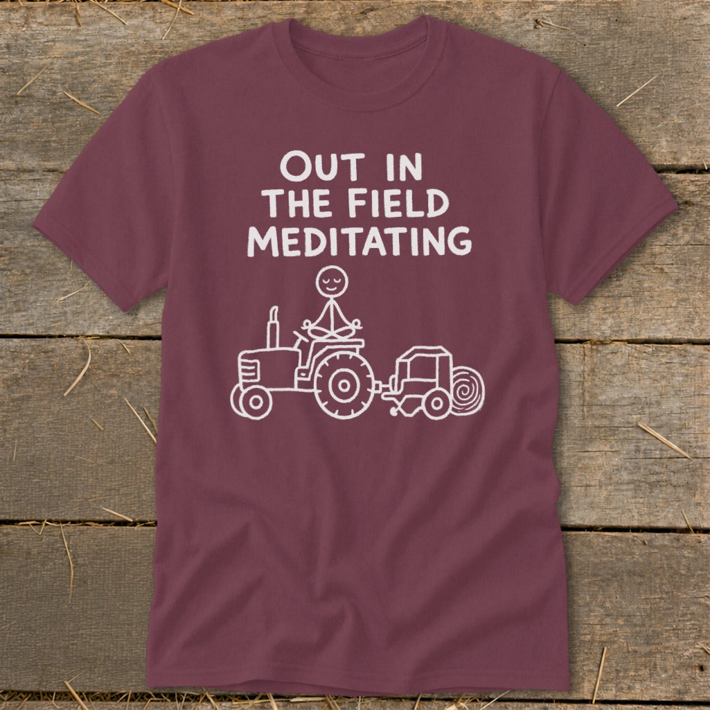 Maroon t-shirt with "OUT IN THE FIELD MEDITATING" and stick figure meditating on tractor.