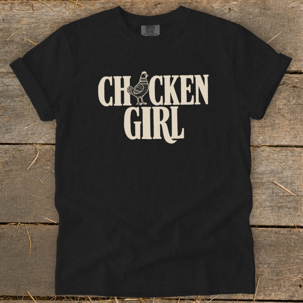Black Comfort Colors shirt with cream text and chicken graphic reading "CHICKEN GIRL".