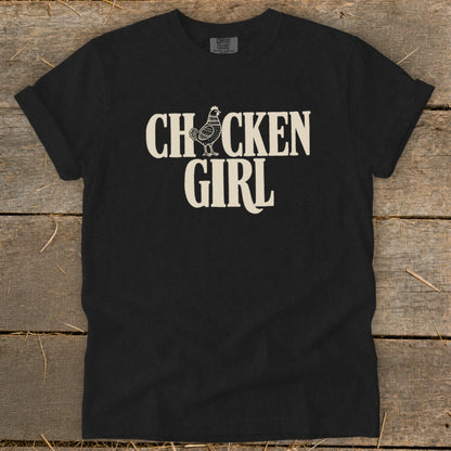 Black Comfort Colors shirt with cream text and chicken graphic reading "CHICKEN GIRL".