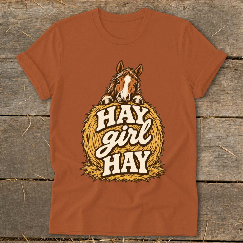 Horse peeking over hay bale with "HAY girl HAY" text on brown t-shirt.