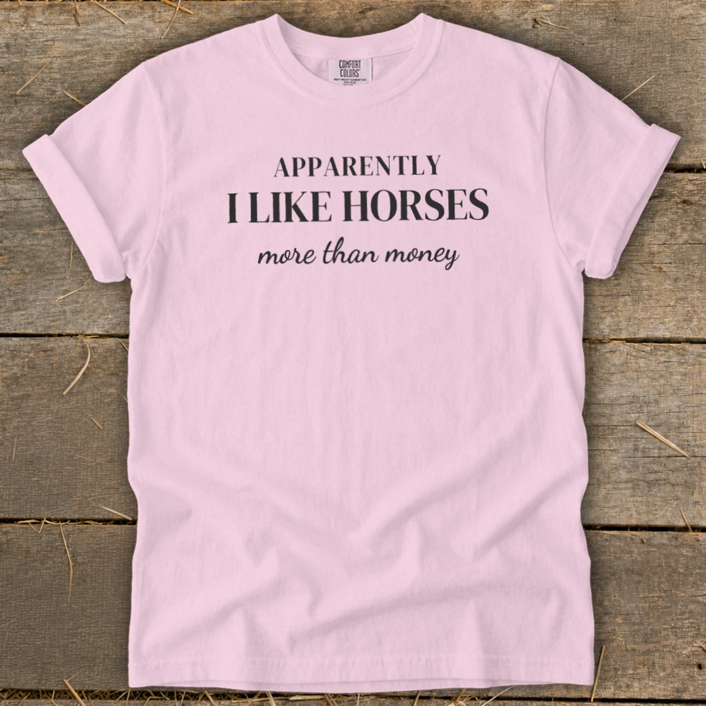Pink t-shirt with black text: "APPARENTLY I LIKE HORSES more than money."