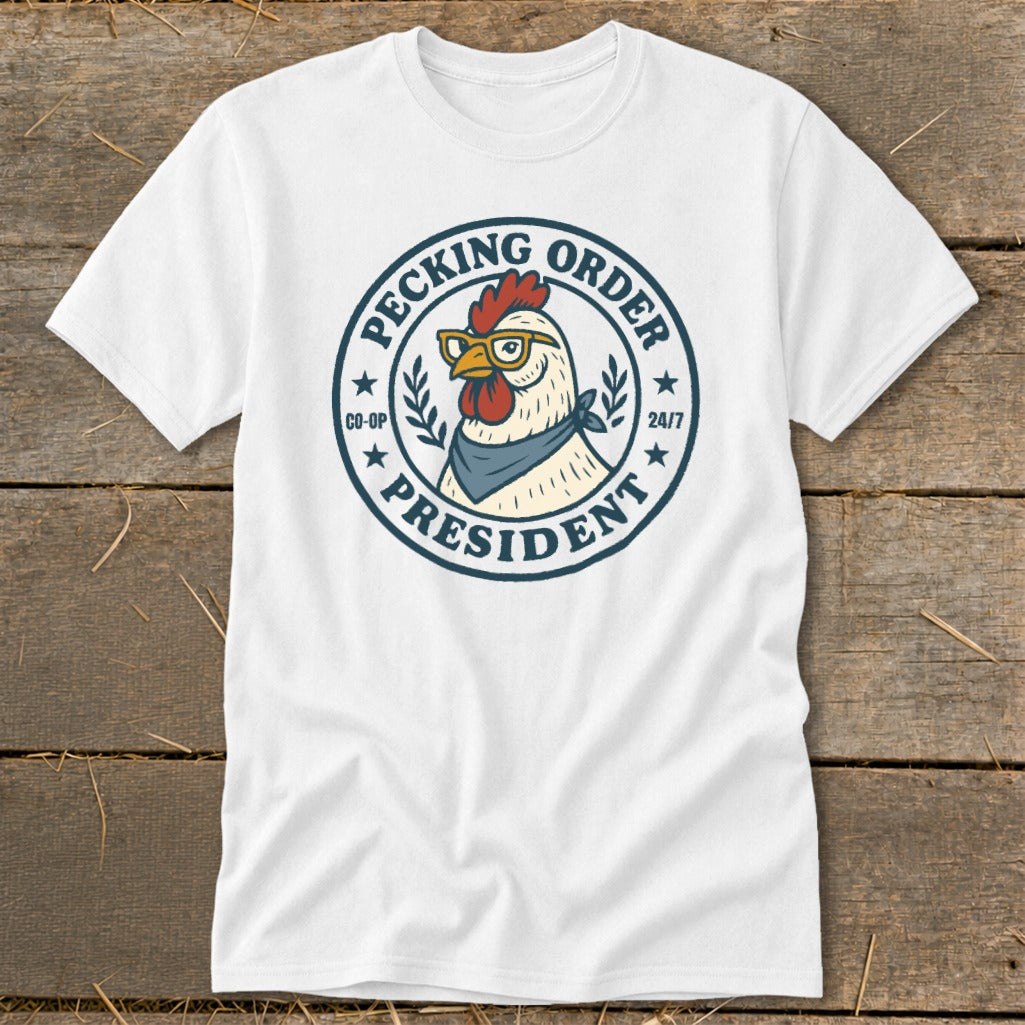 White t-shirt with a circular graphic featuring a chicken wearing glasses and a bandana. Text reads "Pecking Order President Co-Op 24/7".