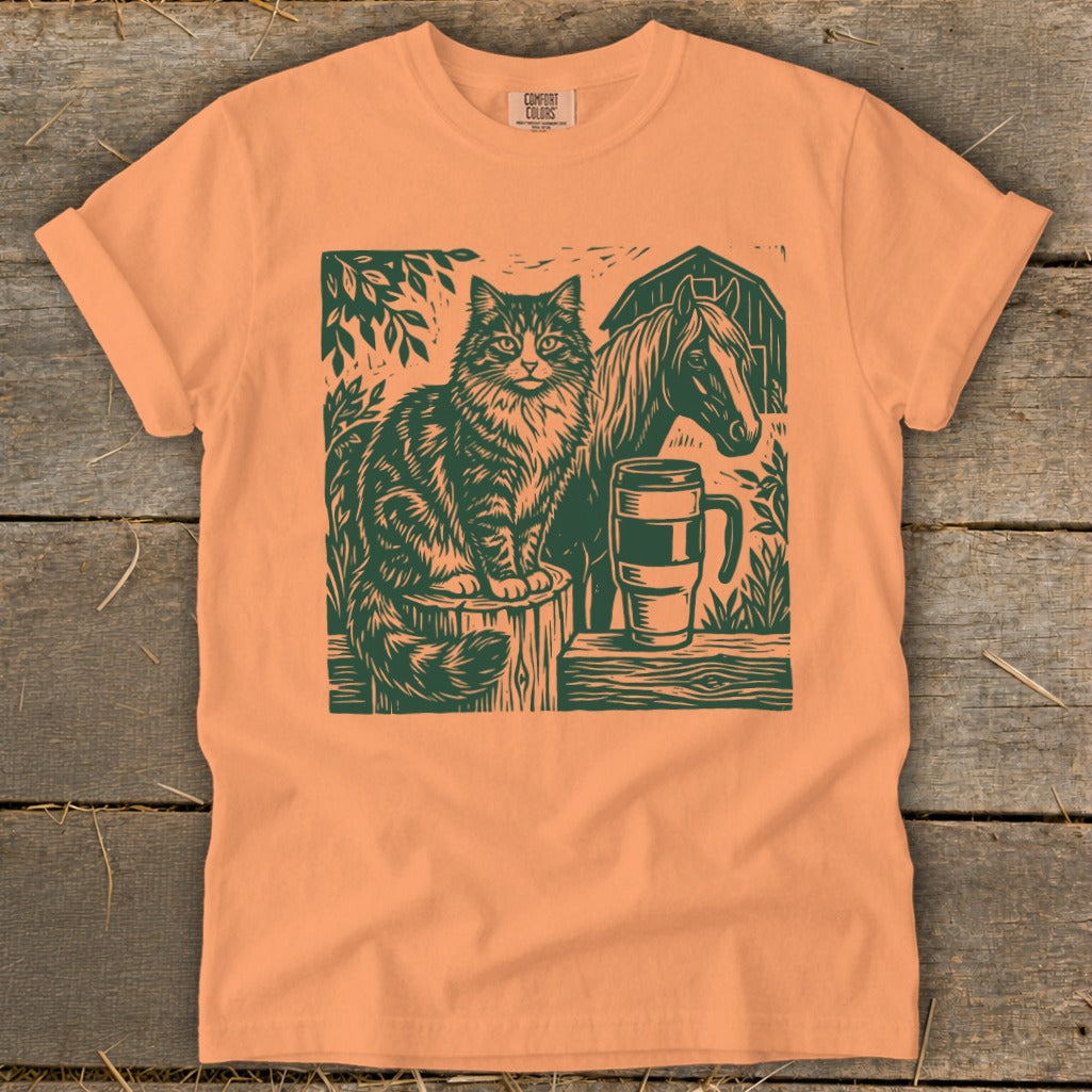 Orange t-shirt with a dark green graphic of a cat, horse, and mug.