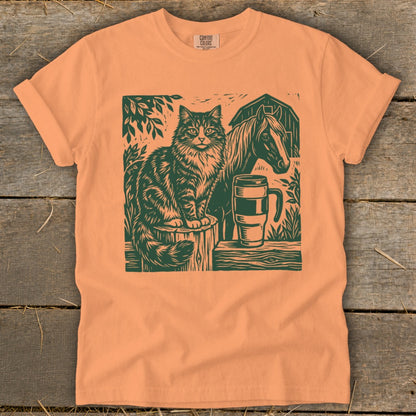 Orange t-shirt with a dark green graphic of a cat, horse, and mug.