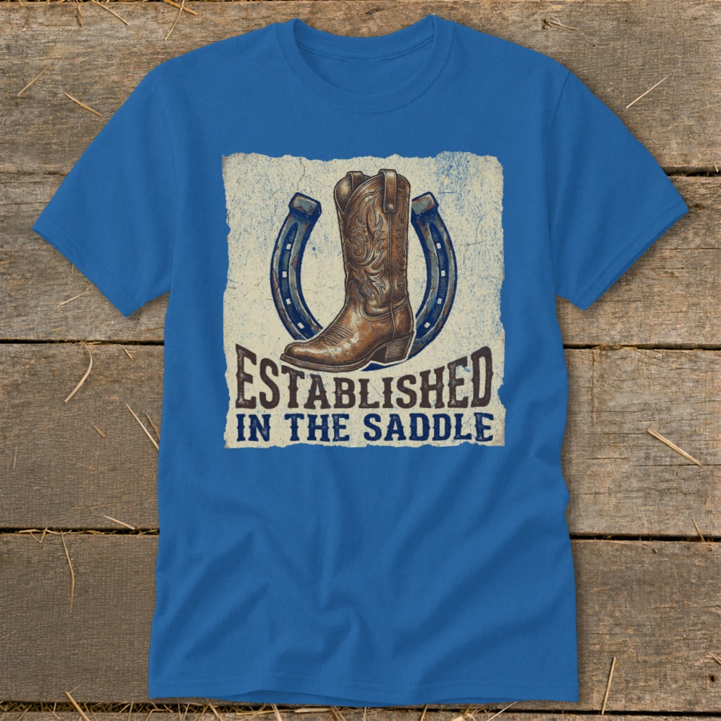Blue t-shirt with graphic of cowboy boot and horseshoes, "Established in the Saddle".