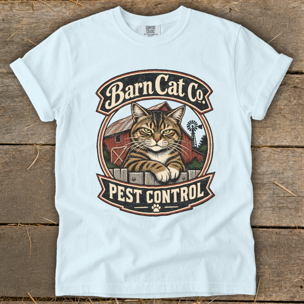 Light blue t-shirt featuring a circular graphic with a tabby cat, red barn, and text reading "Barn Cat Co. Pest Control."