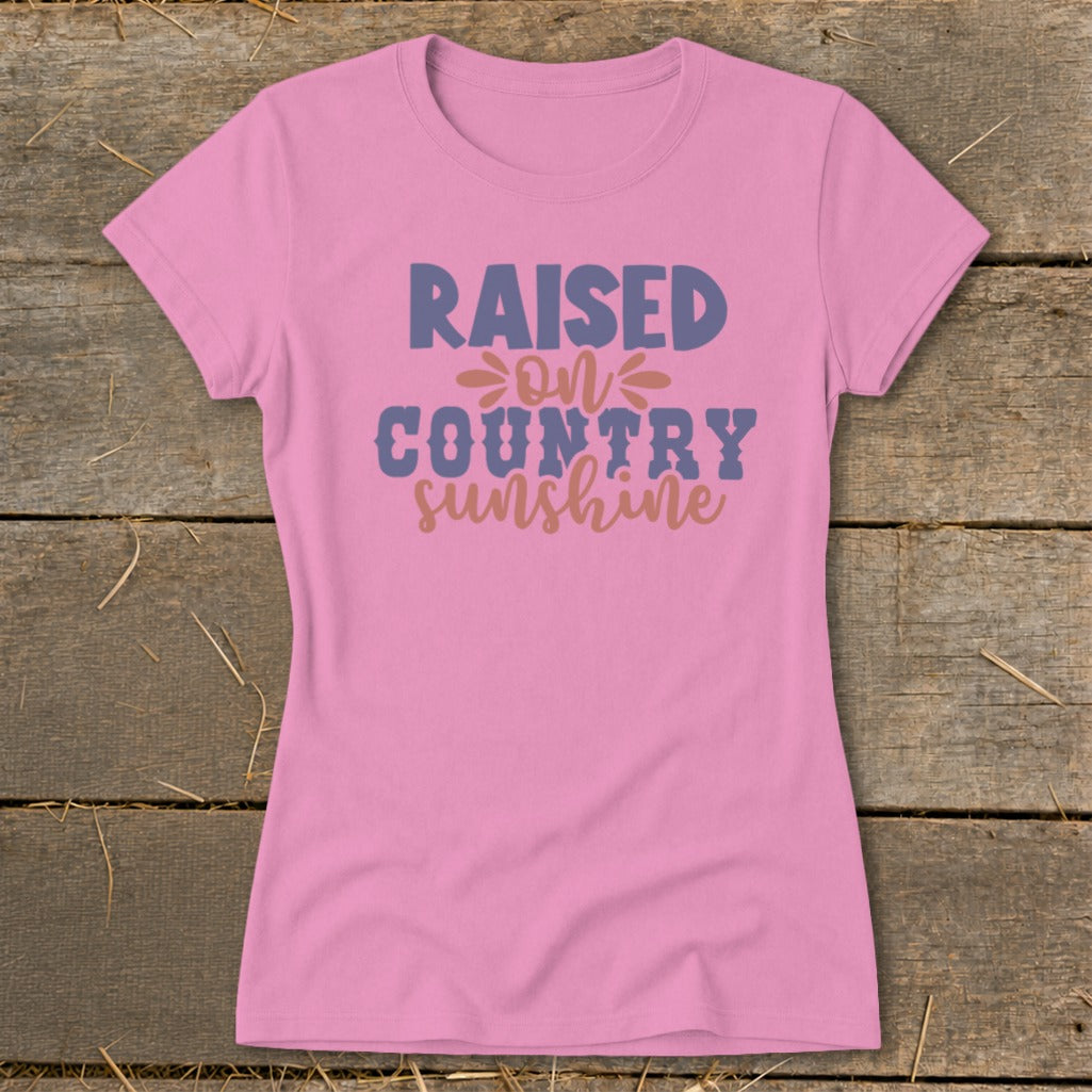 Pink t-shirt with "Raised on Country Sunshine" text graphic.