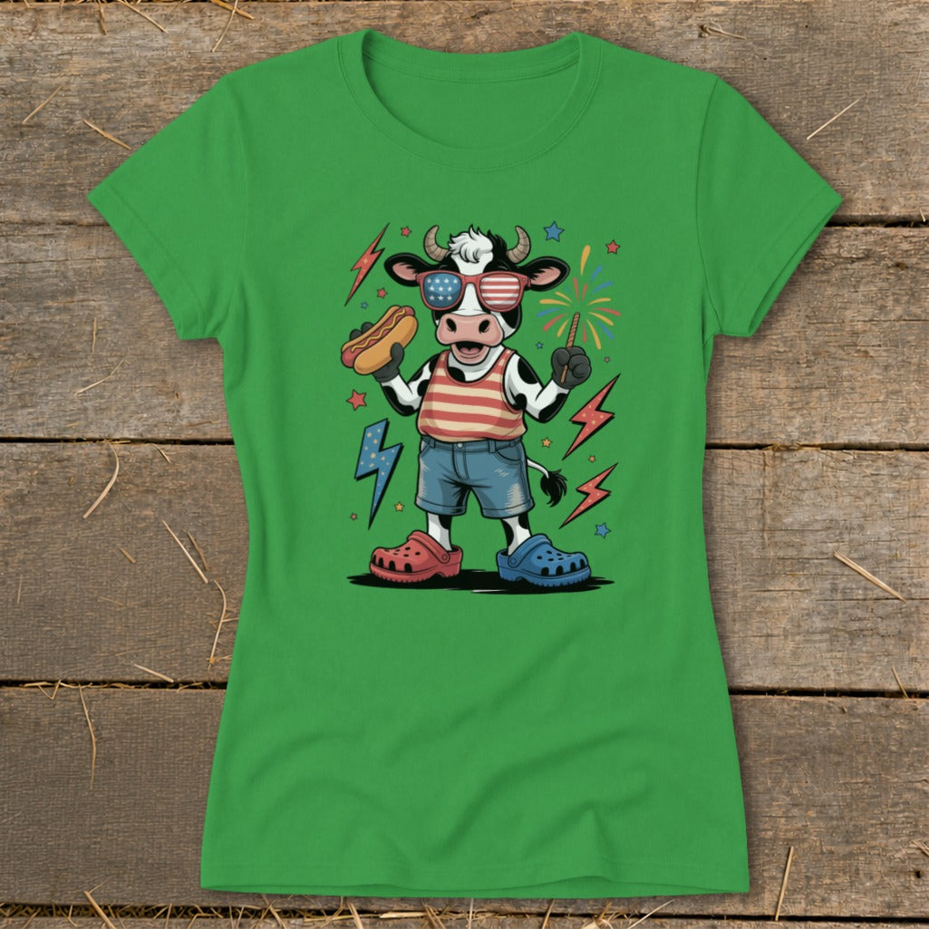 Cartoon cow wearing patriotic sunglasses, holding a hot dog and sparkler.