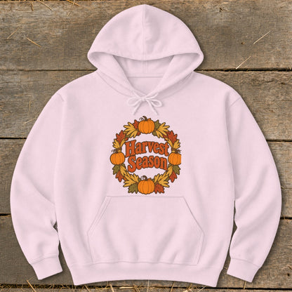 Pink hoodie with "Harvest Season" text within a pumpkin and leaf wreath graphic.