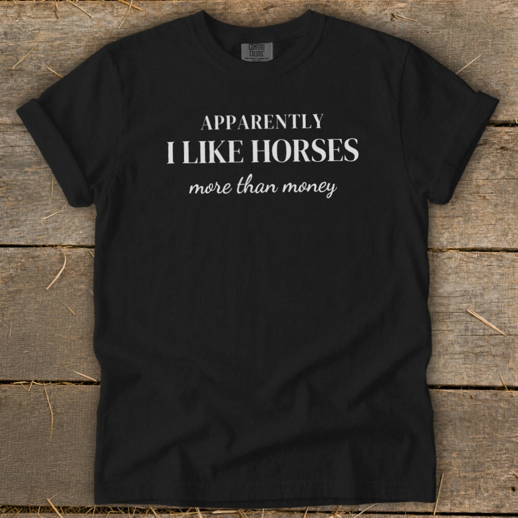 Black t-shirt with white text that says "APPARENTLY I LIKE HORSES more than money".