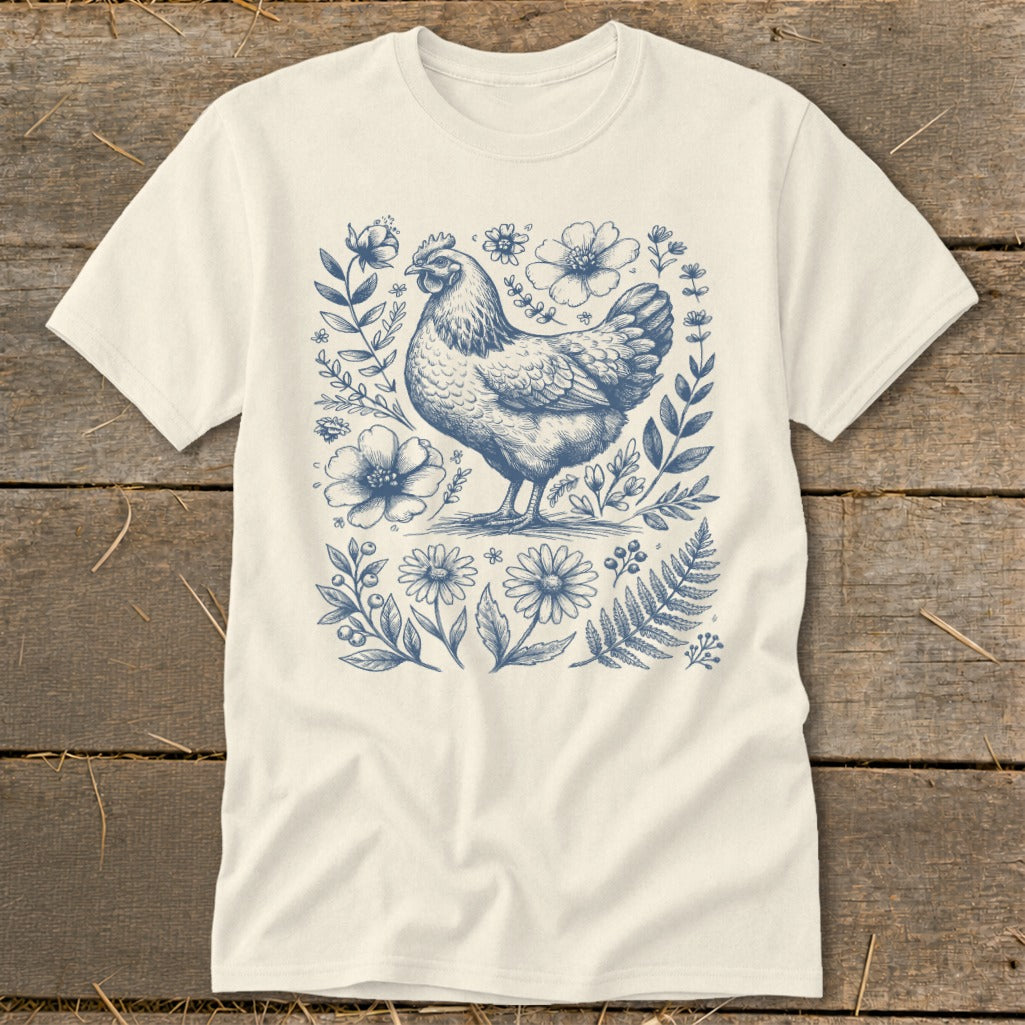 Cream t-shirt with blue ink drawing of a chicken surrounded by flowers and foliage.