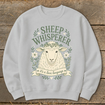 Light grey sweatshirt with "Sheep Whisperer" text and sheep wearing a floral wreath.