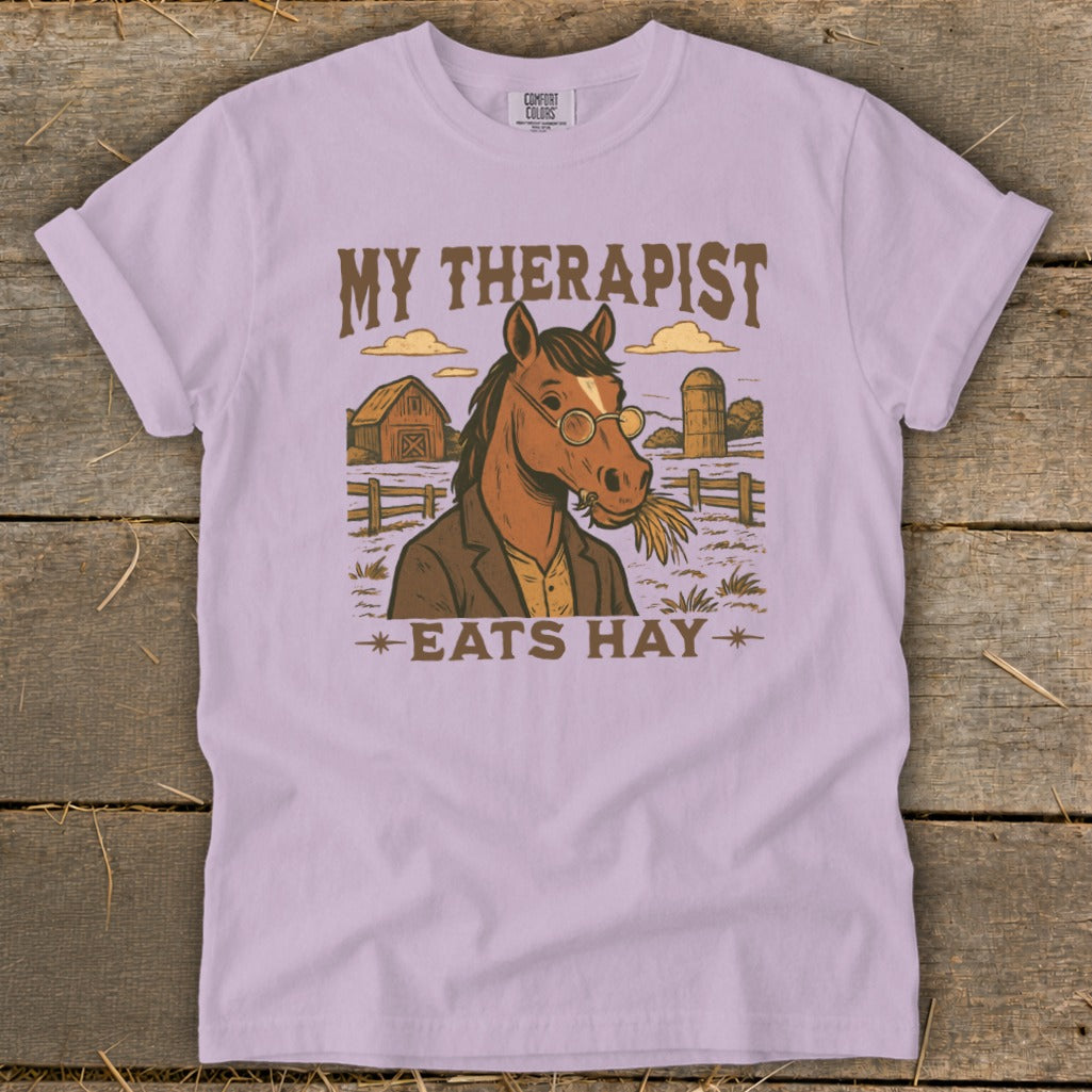 T-shirt graphic with a horse wearing glasses and a jacket, eating hay, with text "MY THERAPIST EATS HAY".