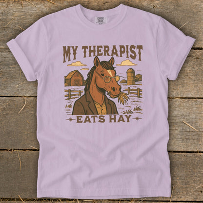 T-shirt graphic with a horse wearing glasses and a jacket, eating hay, with text "MY THERAPIST EATS HAY".