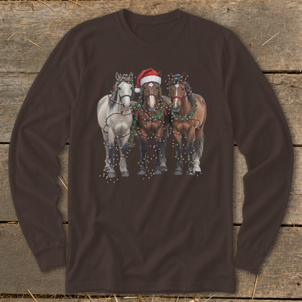 Three horses, one wearing a Santa hat, decorated with Christmas lights and garland.