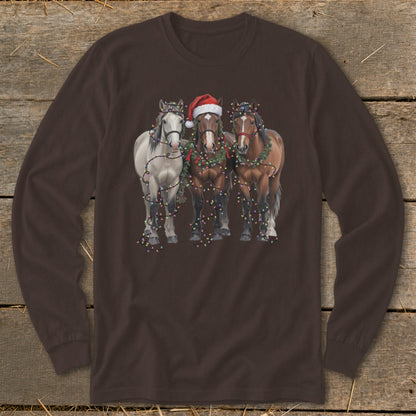 Three horses, one wearing a Santa hat, decorated with Christmas lights and garland.