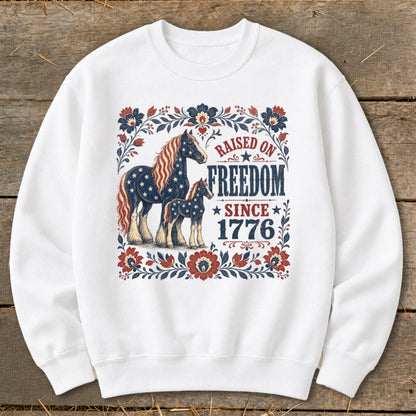 White sweatshirt with American flag-themed horses and "Raised on Freedom Since 1776" text.