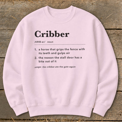 Light pink crewneck sweatshirt featuring humorous dictionary definition text for the word Cribber printed in black.