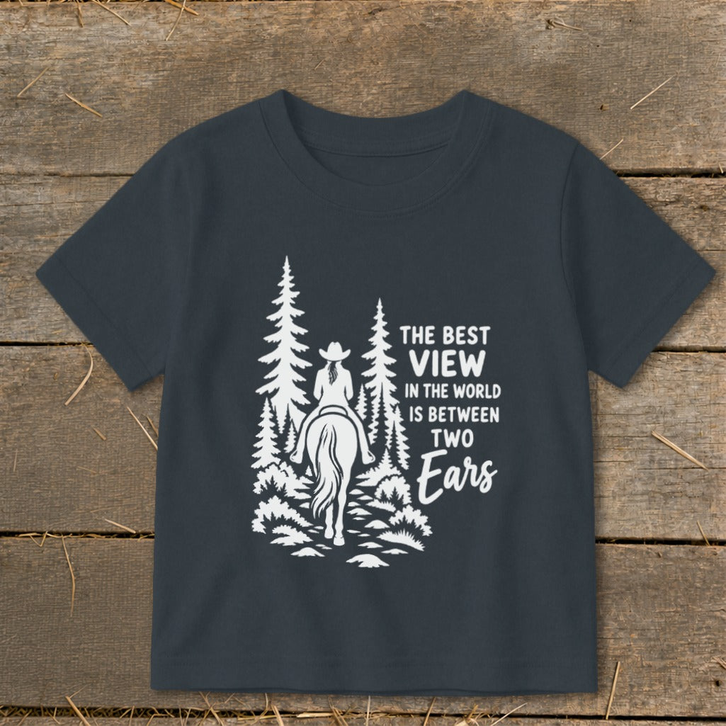 Dark gray short-sleeved t-shirt with a white graphic of a horse and rider amid pine trees and text reading The Best View in the World Is Between Two Ears.