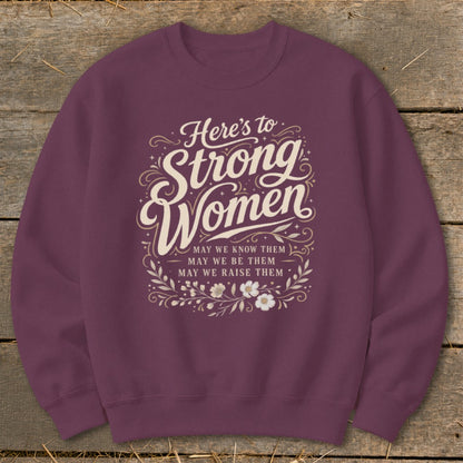 Maroon sweatshirt with text "Here's to Strong Women. May we know them, may we be them, may we raise them."