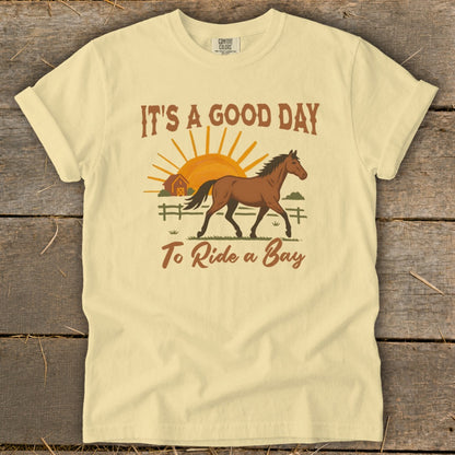 Yellow t-shirt with a graphic of a brown horse, barn, sun, and text "IT'S A GOOD DAY To Ride a Bay".