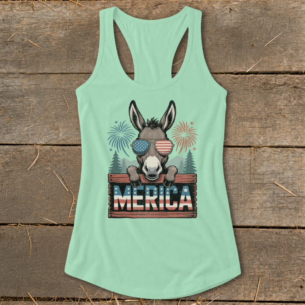 Donkey wearing American flag sunglasses behind "Merica" sign with fireworks.