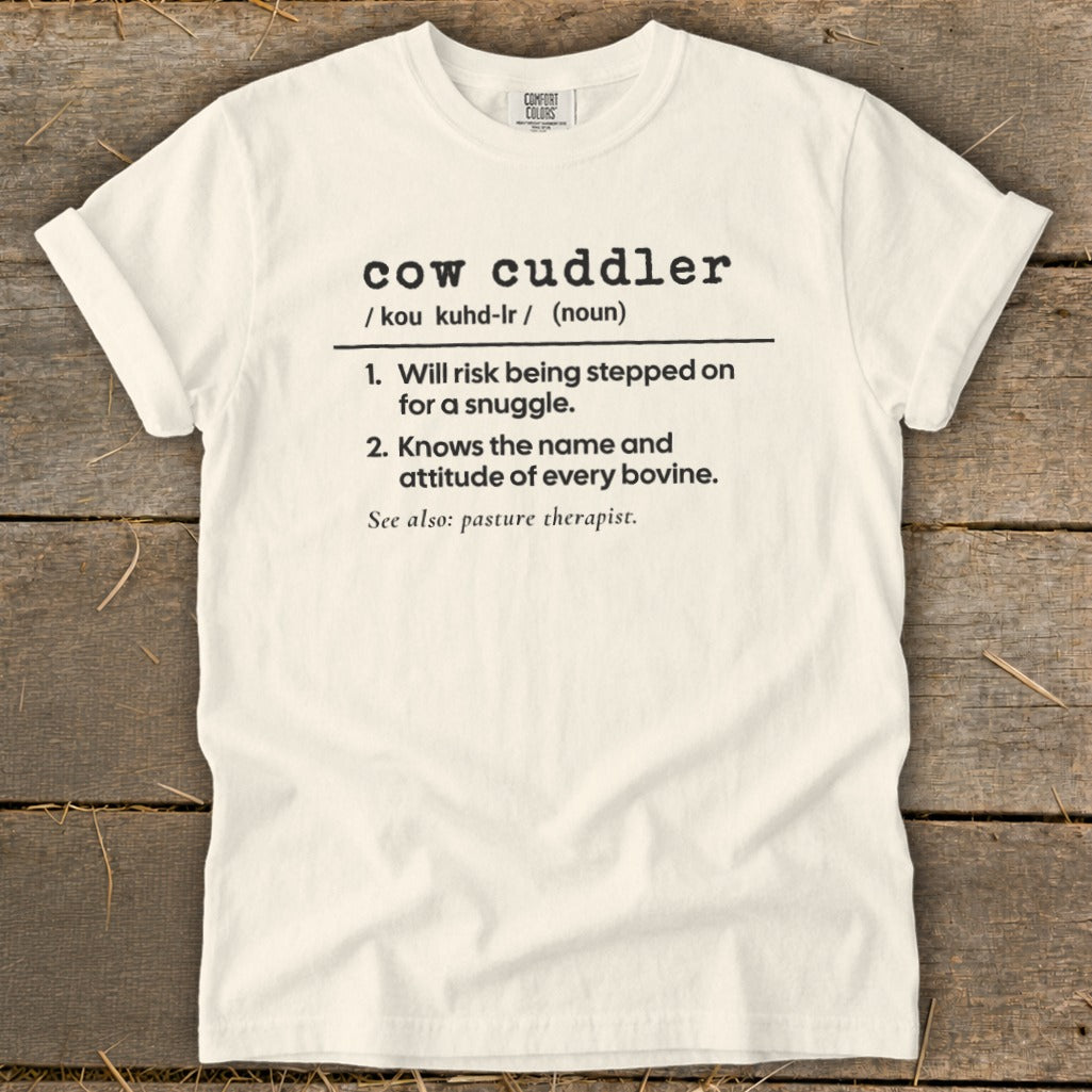White t-shirt with black text defining "cow cuddler" and listing humorous qualities.