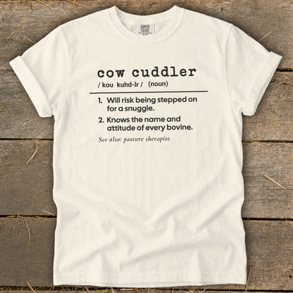 White t-shirt with black text defining "cow cuddler" and listing humorous qualities.