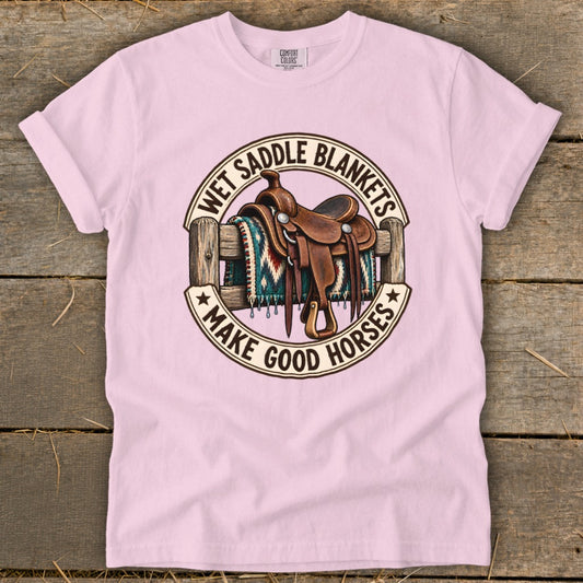 Pink t-shirt graphic with saddle, blanket, fence, and text "Wet Saddle Blankets Make Good Horses".