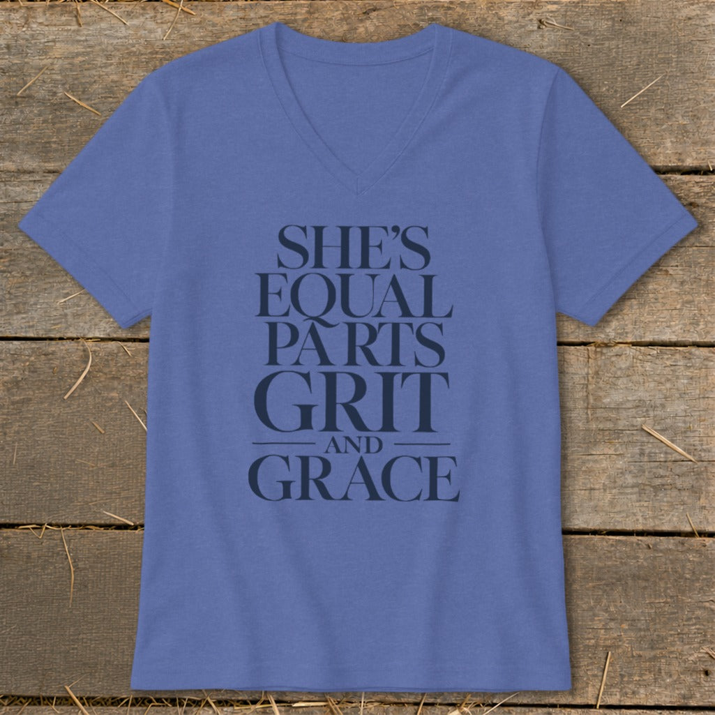 Blue v-neck t-shirt with dark text reading "SHE'S EQUAL PARTS GRIT AND GRACE".