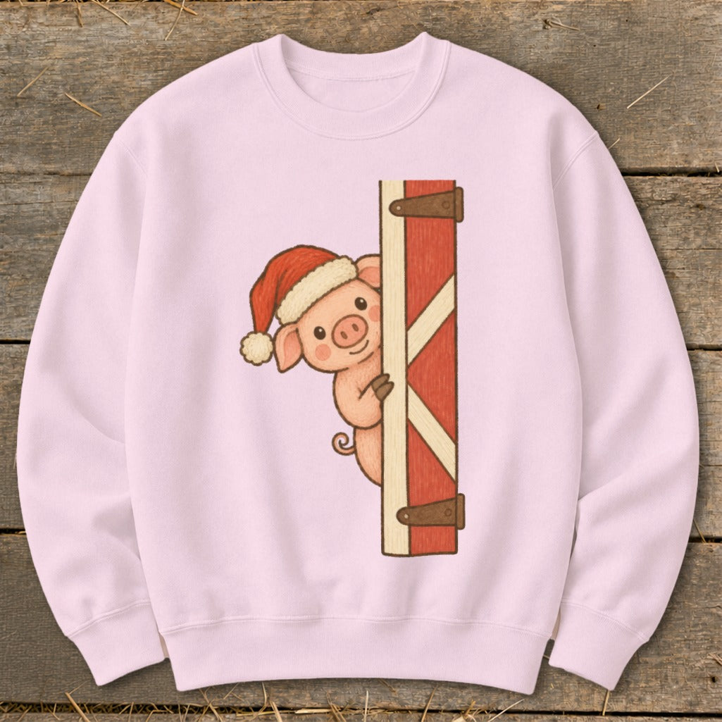 Pink sweatshirt with a cartoon pig wearing a Santa hat peeking behind a barn door.