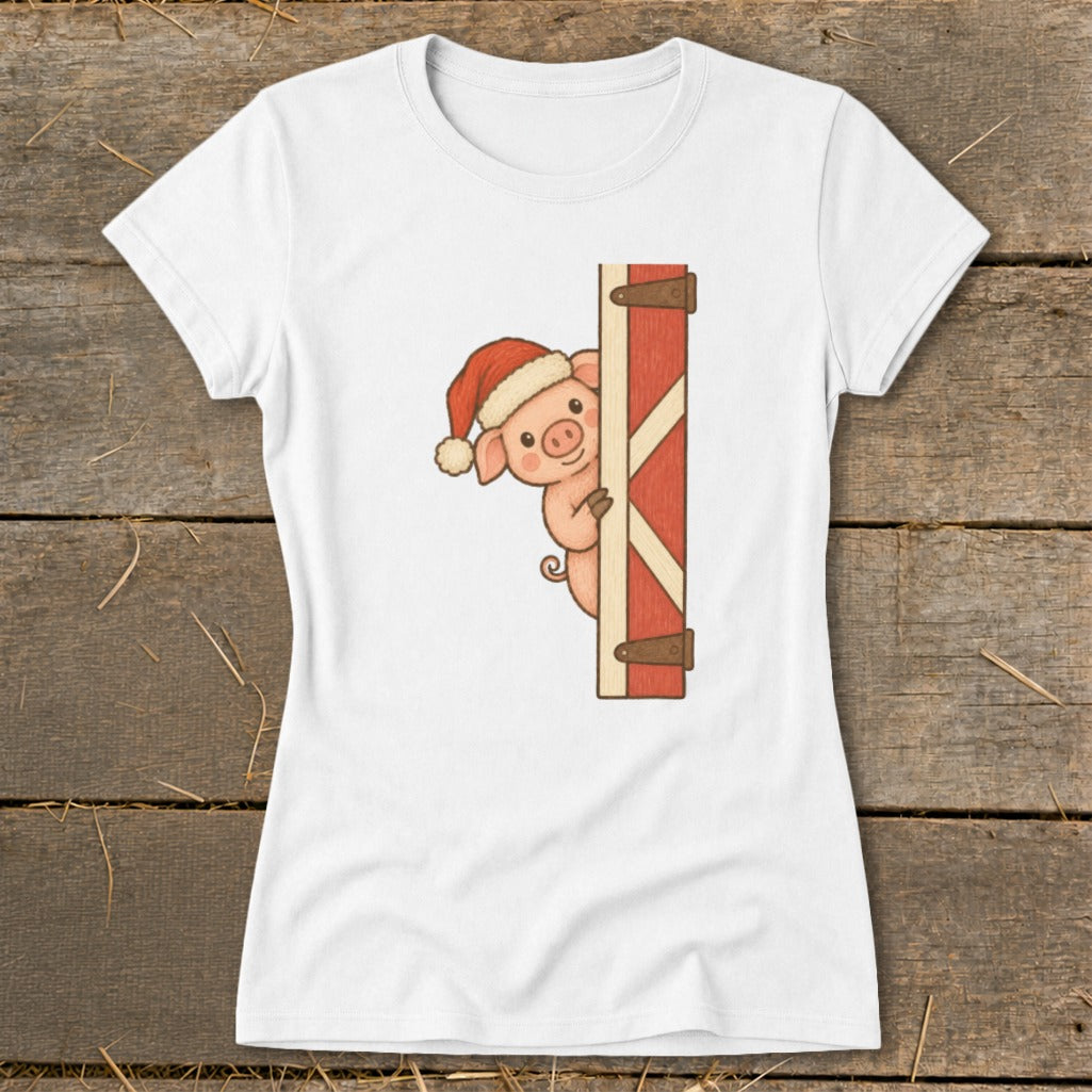 White t-shirt with a cartoon pig wearing a Santa hat peeking from behind a red barn door.