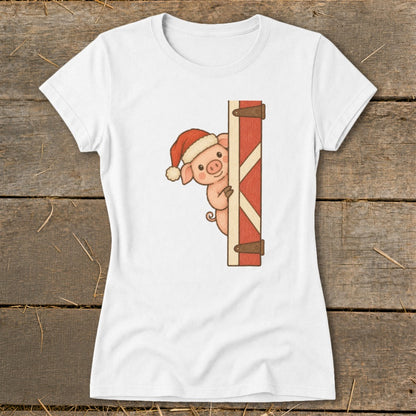 White t-shirt with a cartoon pig wearing a Santa hat peeking from behind a red barn door.