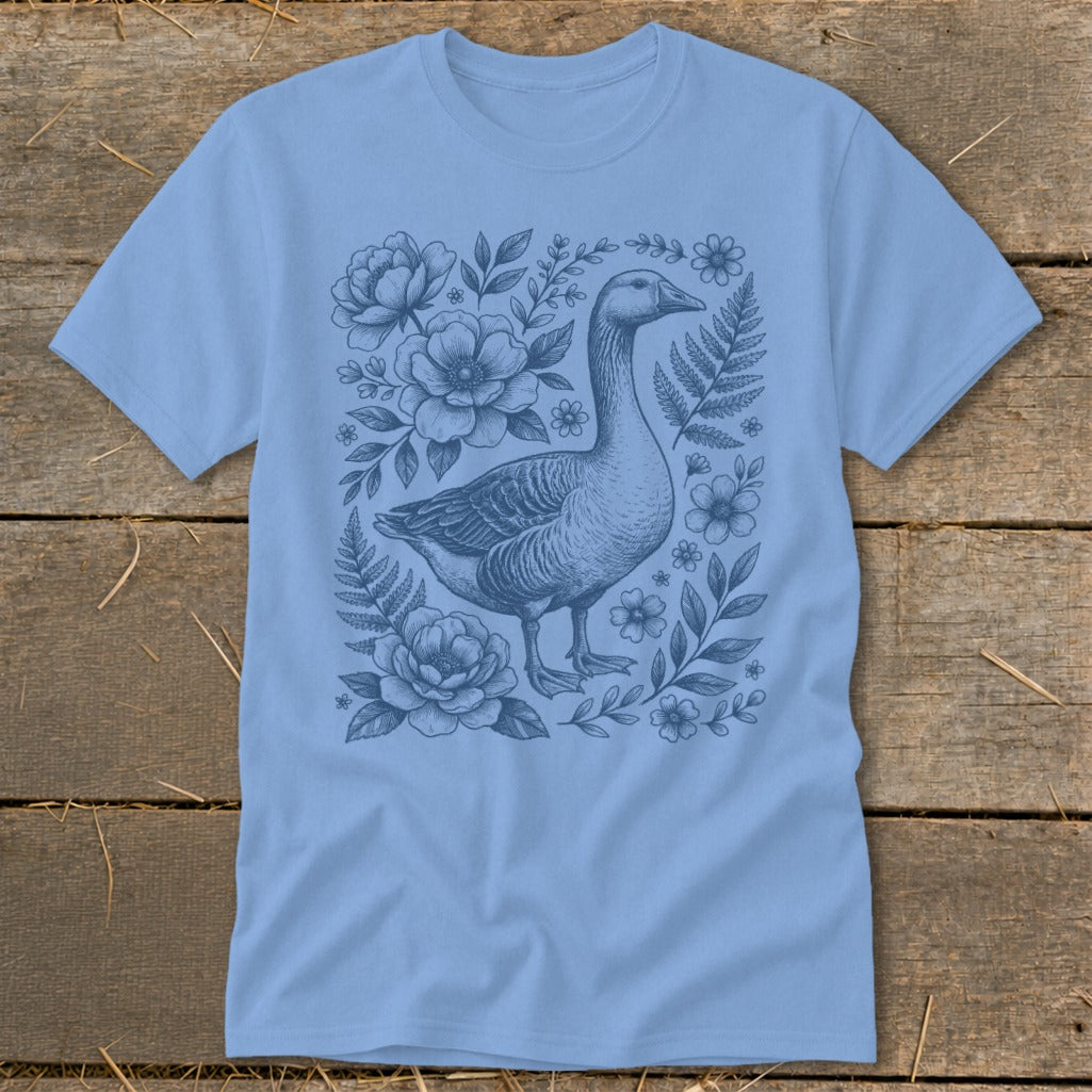 Light blue t-shirt with a blue ink illustration of a goose surrounded by flowers and ferns.