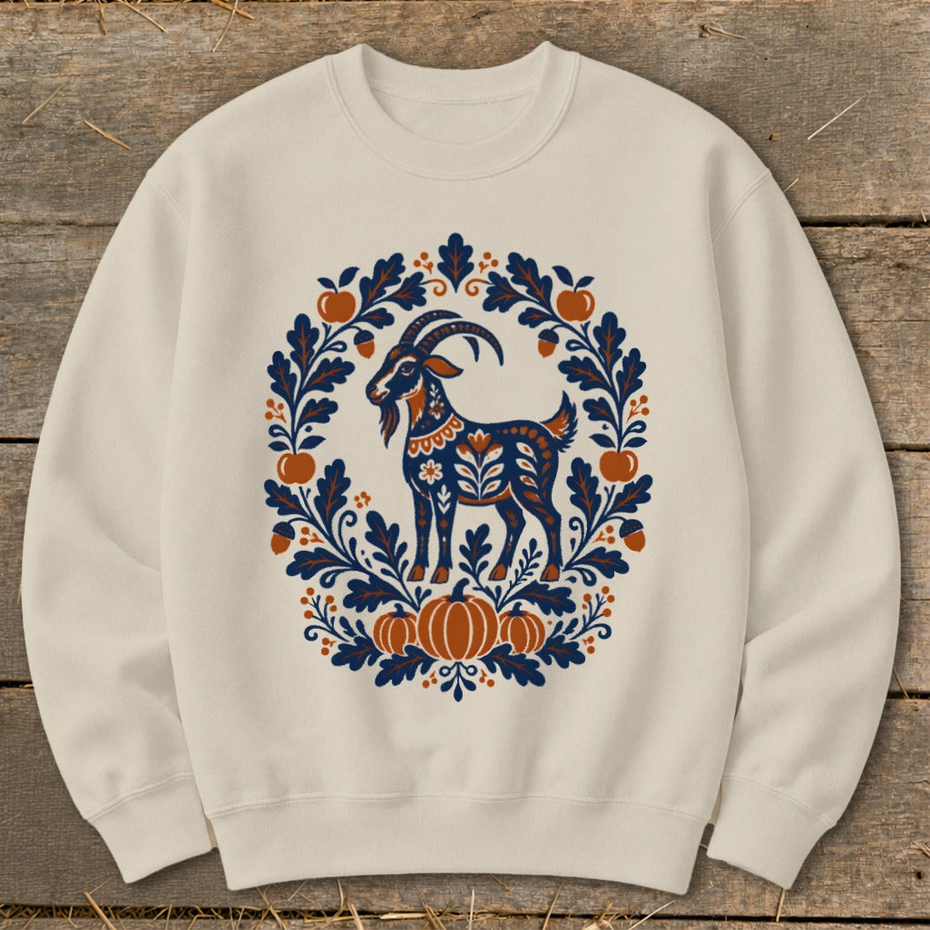 Off-white crewneck sweatshirt featuring a folkloric graphic of a patterned goat surrounded by autumn leaves and pumpkins.