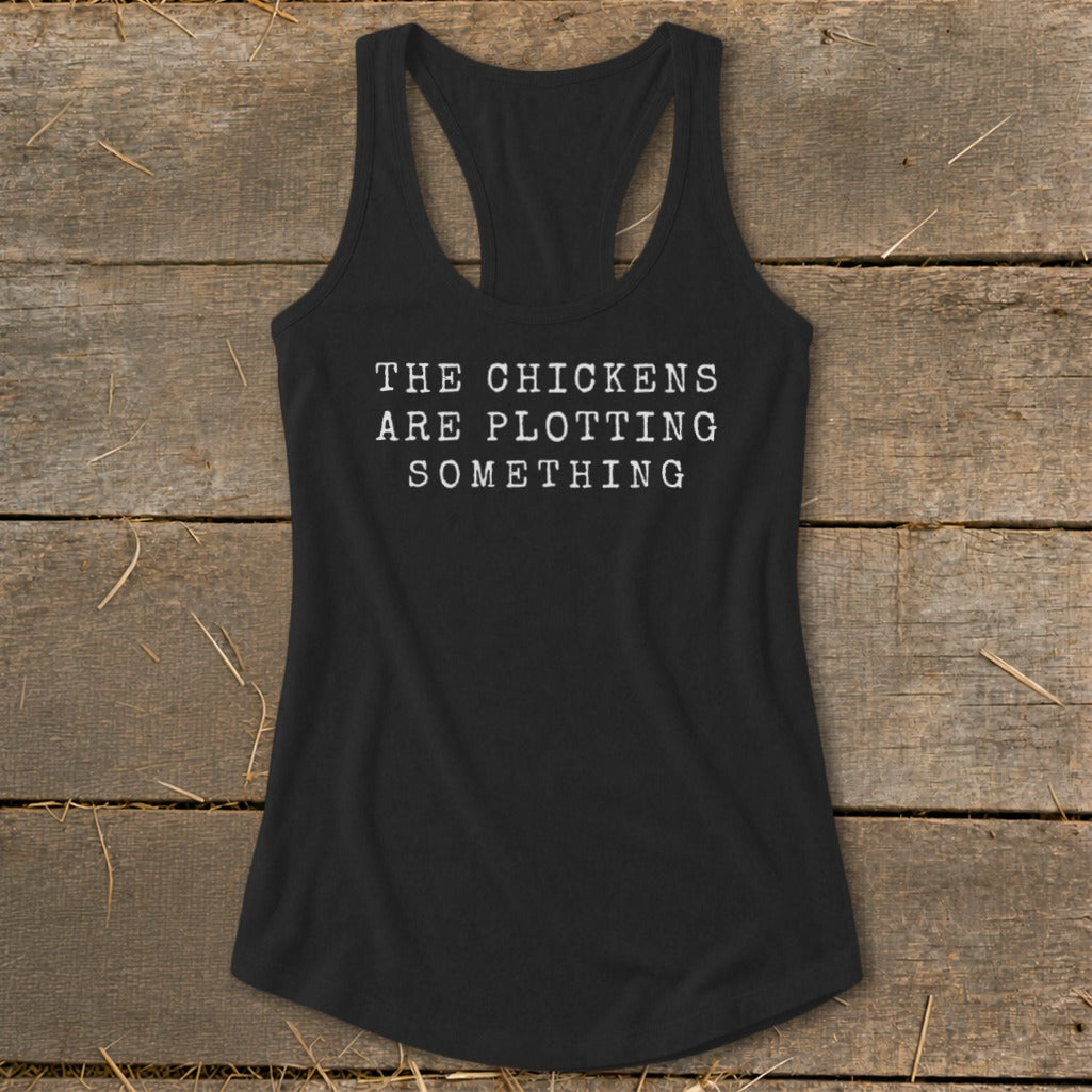 Black racerback tank top with white text reading "THE CHICKENS ARE PLOTTING SOMETHING".