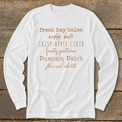 White long-sleeve shirt with text: fresh hay bales, muddy boots, crisp apple cider, frosty pastures, pumpkin patch, flannel shirts.