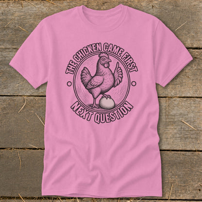 Pink t-shirt with illustration of chicken on egg, text "The chicken came first" and "Next question".
