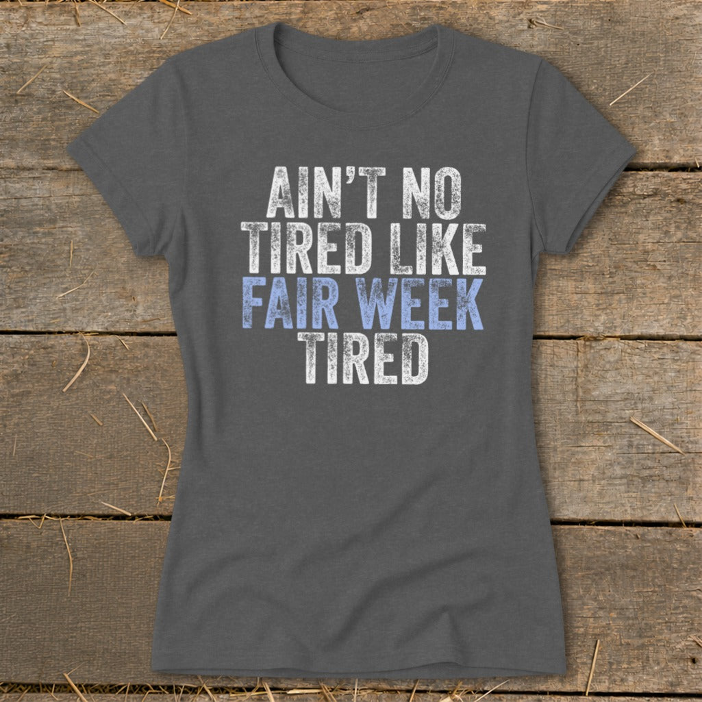 Dark grey t-shirt with distressed text: "AIN'T NO TIRED LIKE FAIR WEEK TIRED."
