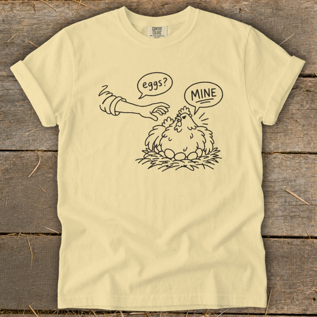 T-shirt with line drawing of chicken on nest, saying "MINE" to a hand asking "eggs?".