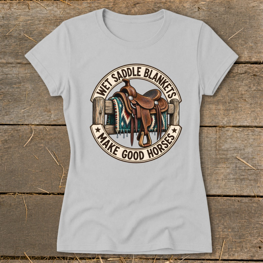 Light gray t-shirt with a graphic of a saddle on a fence and text "Wet Saddle Blankets Make Good Horses".