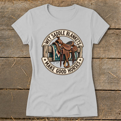Light gray t-shirt with a graphic of a saddle on a fence and text "Wet Saddle Blankets Make Good Horses".
