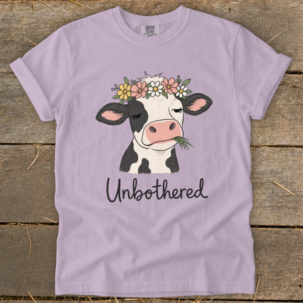 T-shirt with illustration of a cow wearing a flower crown and eating grass, text "Unbothered".